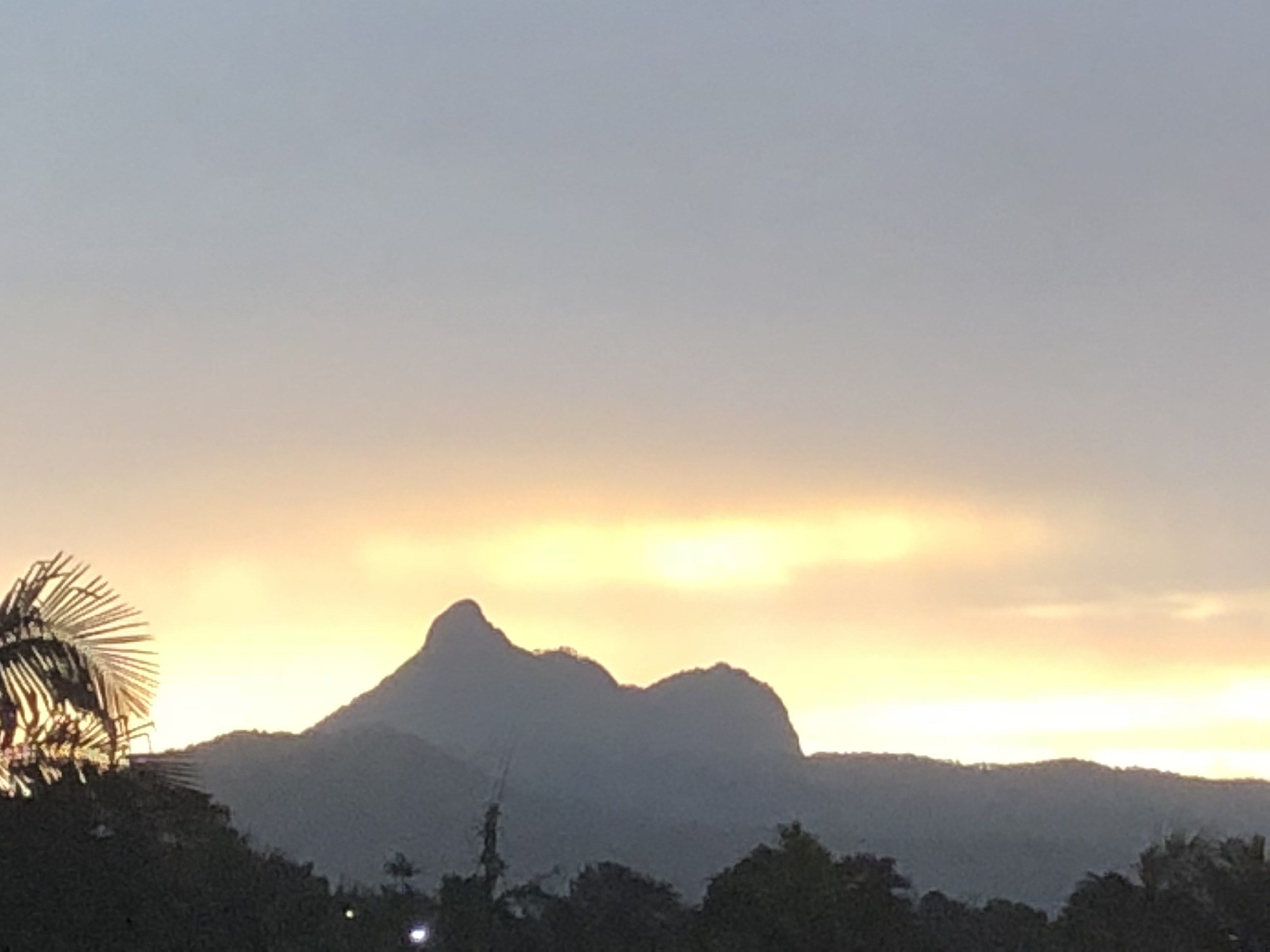 A mountain silhouette against a sunset sky.