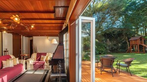 A cozy living area with a fireplace, comfortable seating, and a view of the garden. - Pousada Monte Felice Recanto da Lua (Gramado)