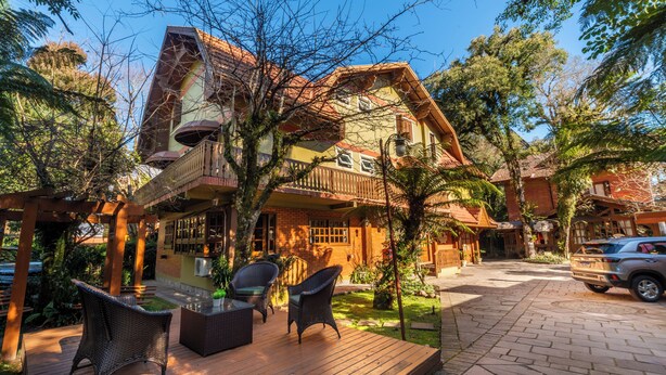 A house with a balcony, outdoor seating, and a garden. - Pousada Monte Felice Recanto da Lua (Gramado)