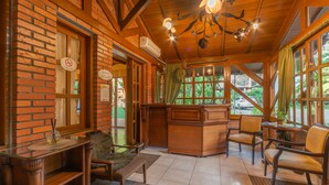 A cozy room with a wooden desk, a bench, and a reception desk. - Pousada Monte Felice Recanto da Lua (Gramado)