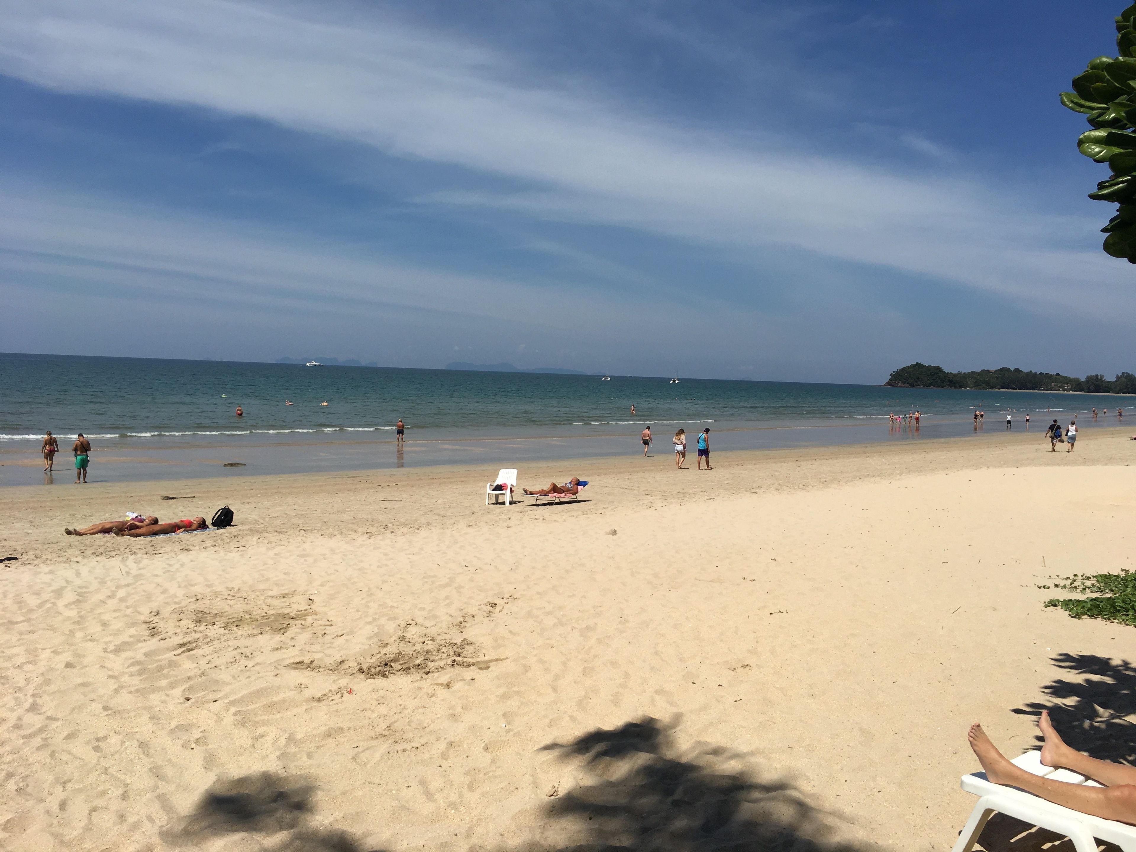Una playa con gente tomando el sol y nadando.