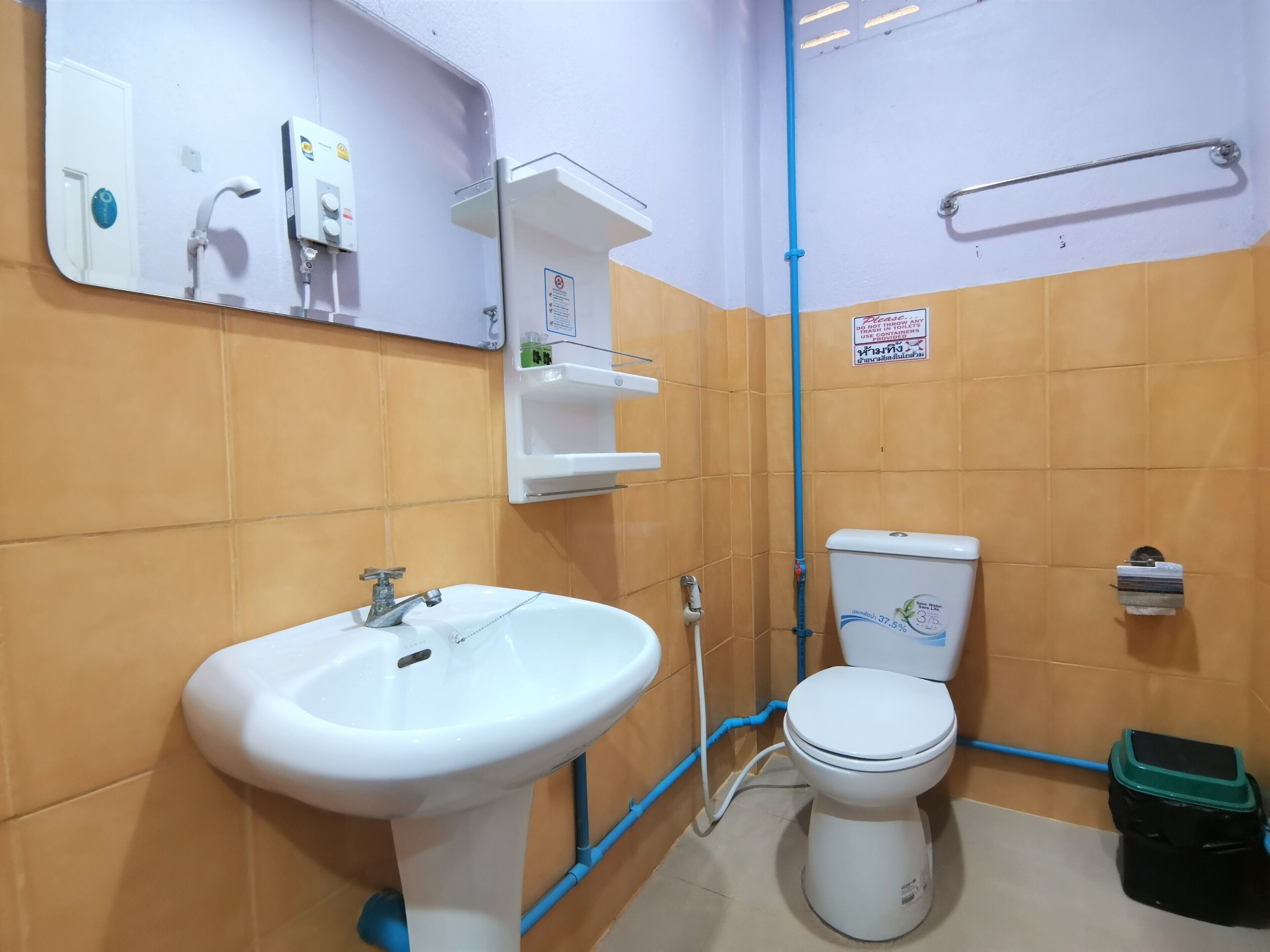 A bathroom with a white sink, a toilet, and a mirror. There are shelves above the sink and a towel rack on the wall.