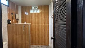 A bathroom with a toilet, shower, and patterned floor tiles.