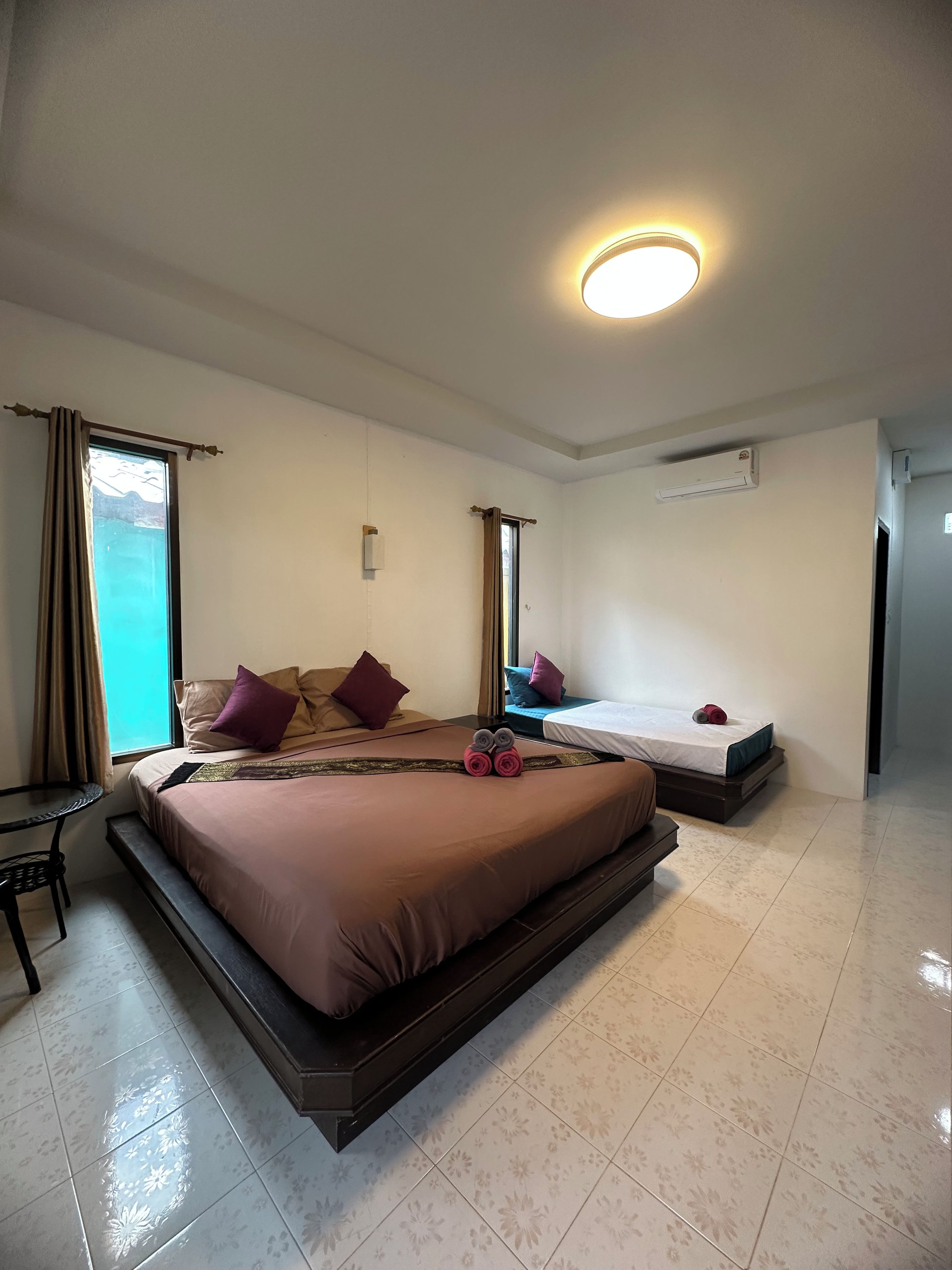 Habitación de hotel con una cama grande, una cama más pequeña, un escritorio y una ventana con cortinas.