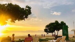 A beach scene with lounge chairs and a view of the ocean at sunset. - Lanta Garden Home (Ko Lanta)