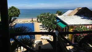 A view of a beach with a pool, lounge chairs, and a thatched-roof building. - Lanta Garden Home (Ko Lanta)