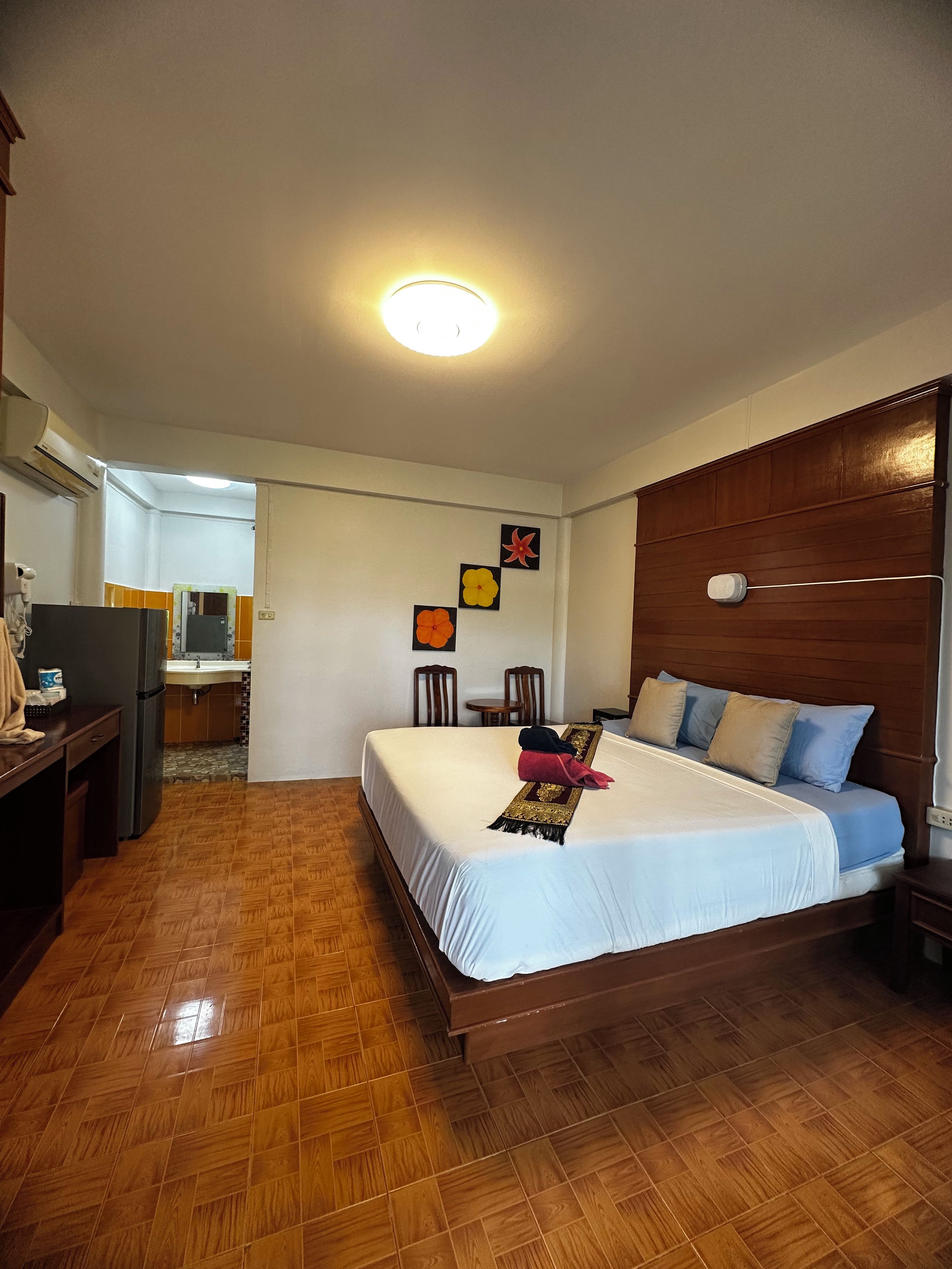 A hotel room with a bed, wooden headboard, a small table, and a mirror.