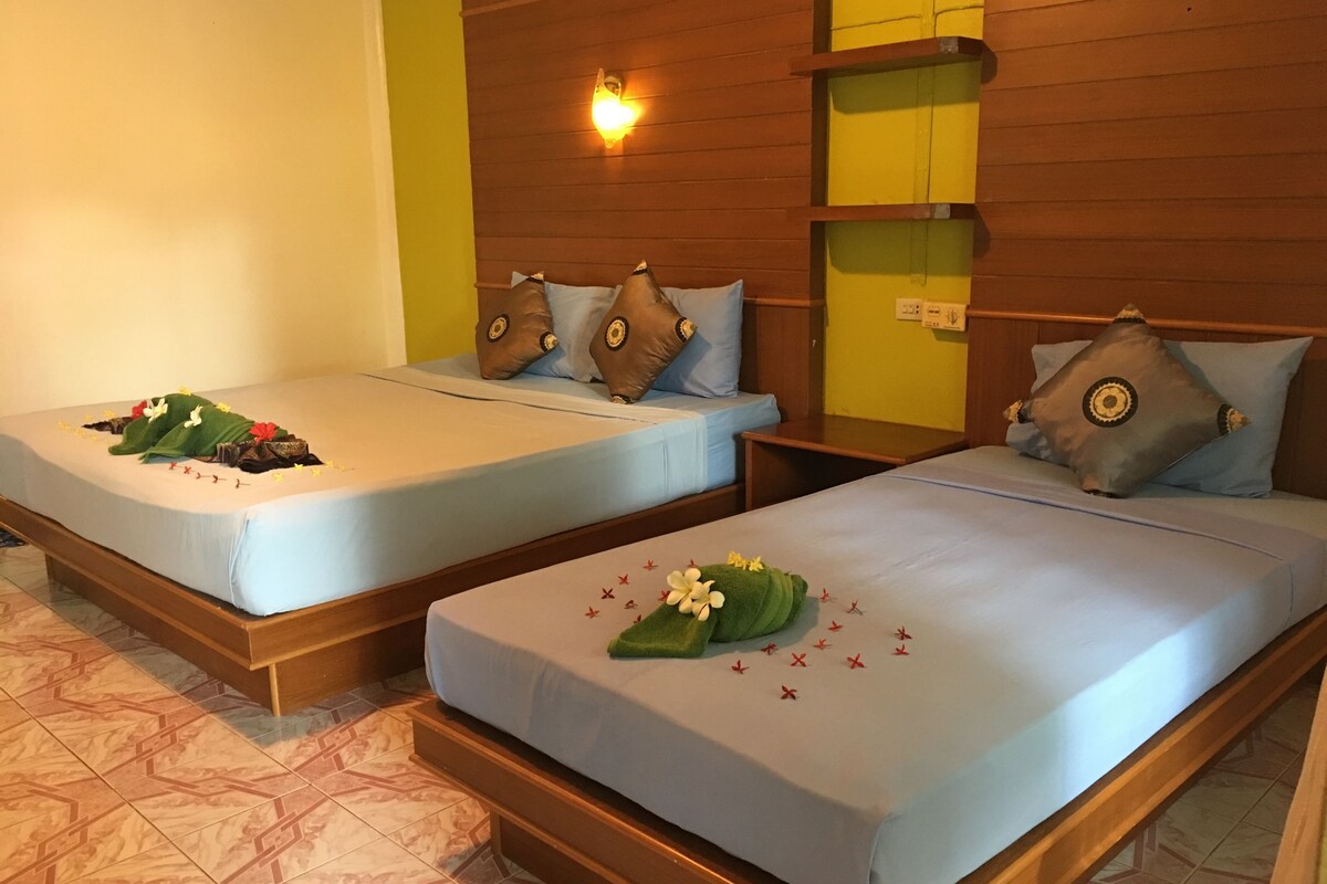 Two single beds with wooden headboards, each with a pillow and a small bedside table.