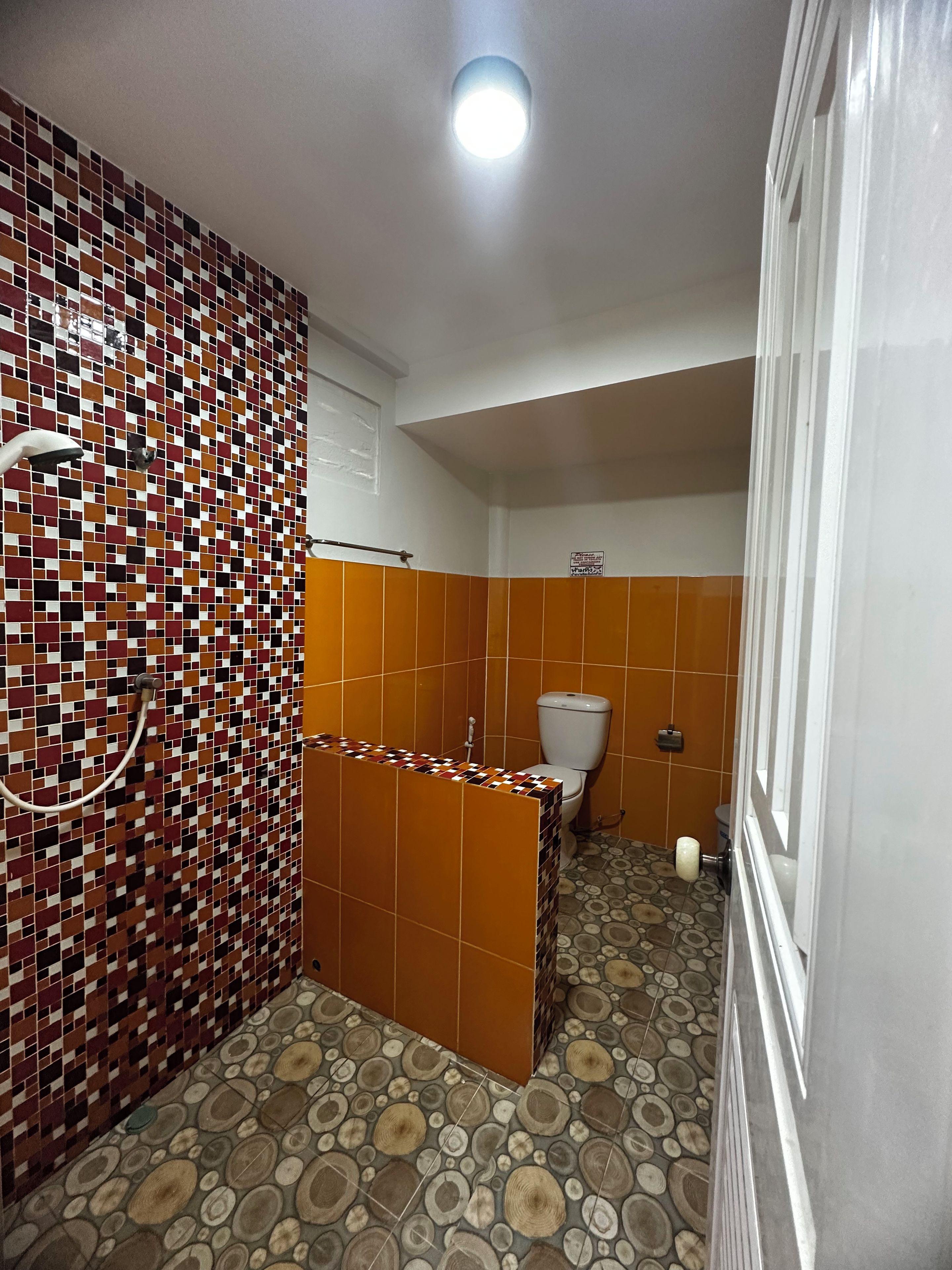 A bathroom with a tiled shower area, a toilet, and a sink.