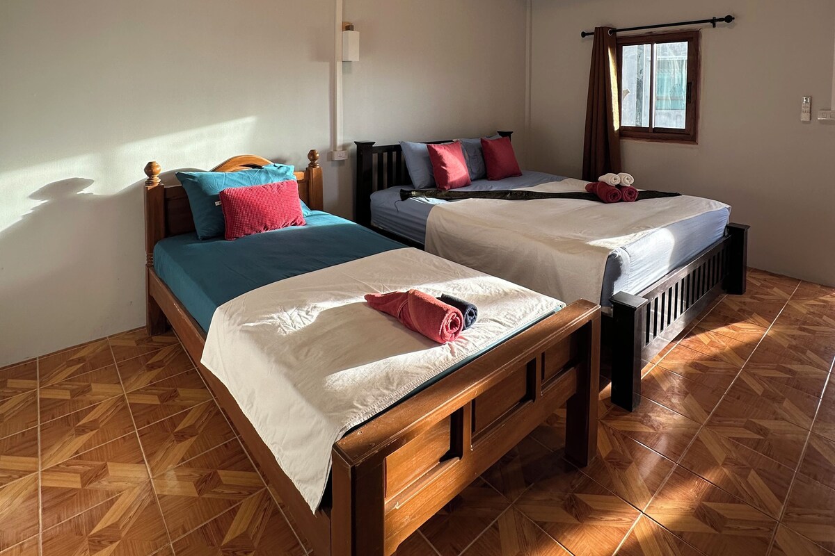 A room with two beds, a window with curtains, and a ceiling light.