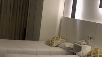 Una habitación de hotel con dos camas, una mesita de noche y un teléfono, además de una cortina.