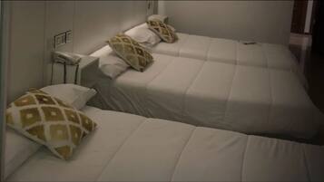 Une chambre d’hôtel avec deux lits, chacun étant équipé de draps blancs et d’oreillers à motifs.