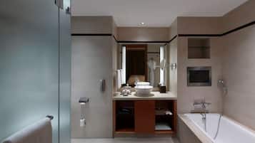 A modern bathroom with a glass shower enclosure, a freestanding bathtub, and a vanity with a sink and mirror.