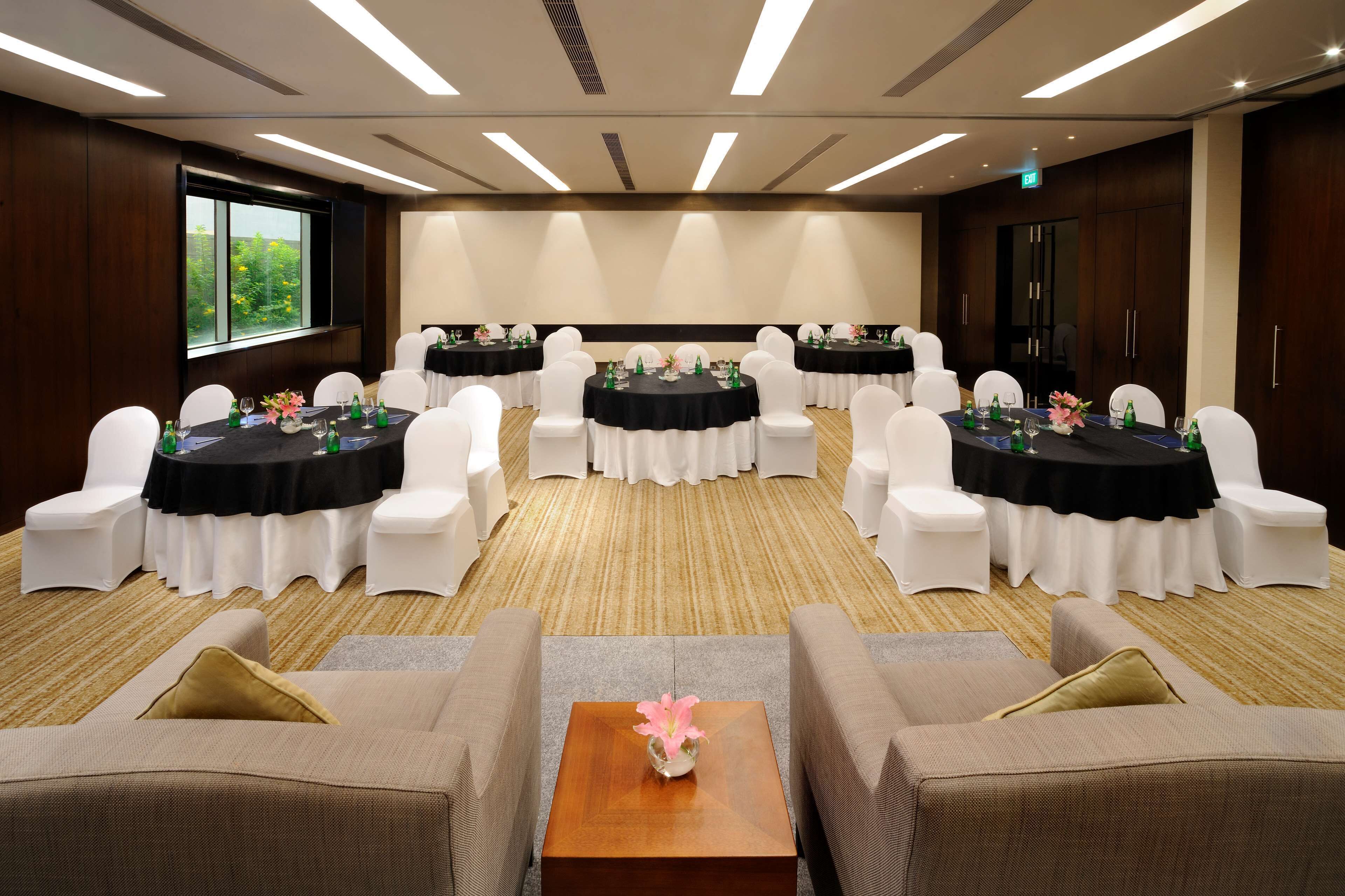 A conference room with round tables, white chairs, and a central sofa.