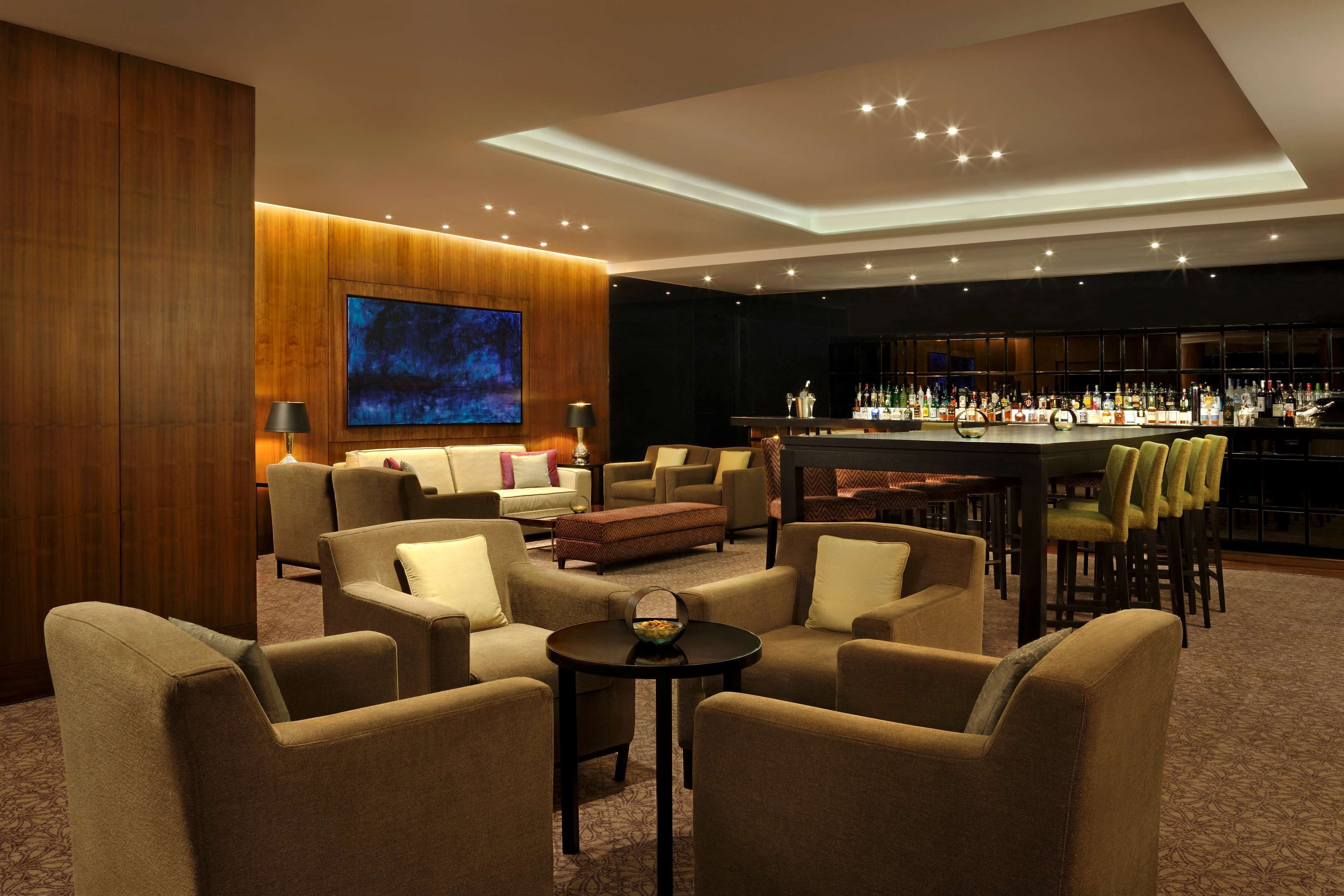 A modern lounge area with comfortable seating, a bar, and a large screen.