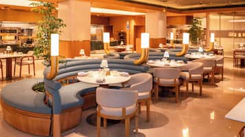 A modern restaurant with curved seating areas, wooden tables, and ambient lighting.