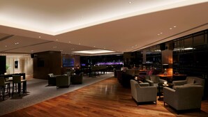 A spacious lounge area with a bar, seating arrangements, and a large screen. - Hilton Bangalore Embassy GolfLinks (Bengaluru)