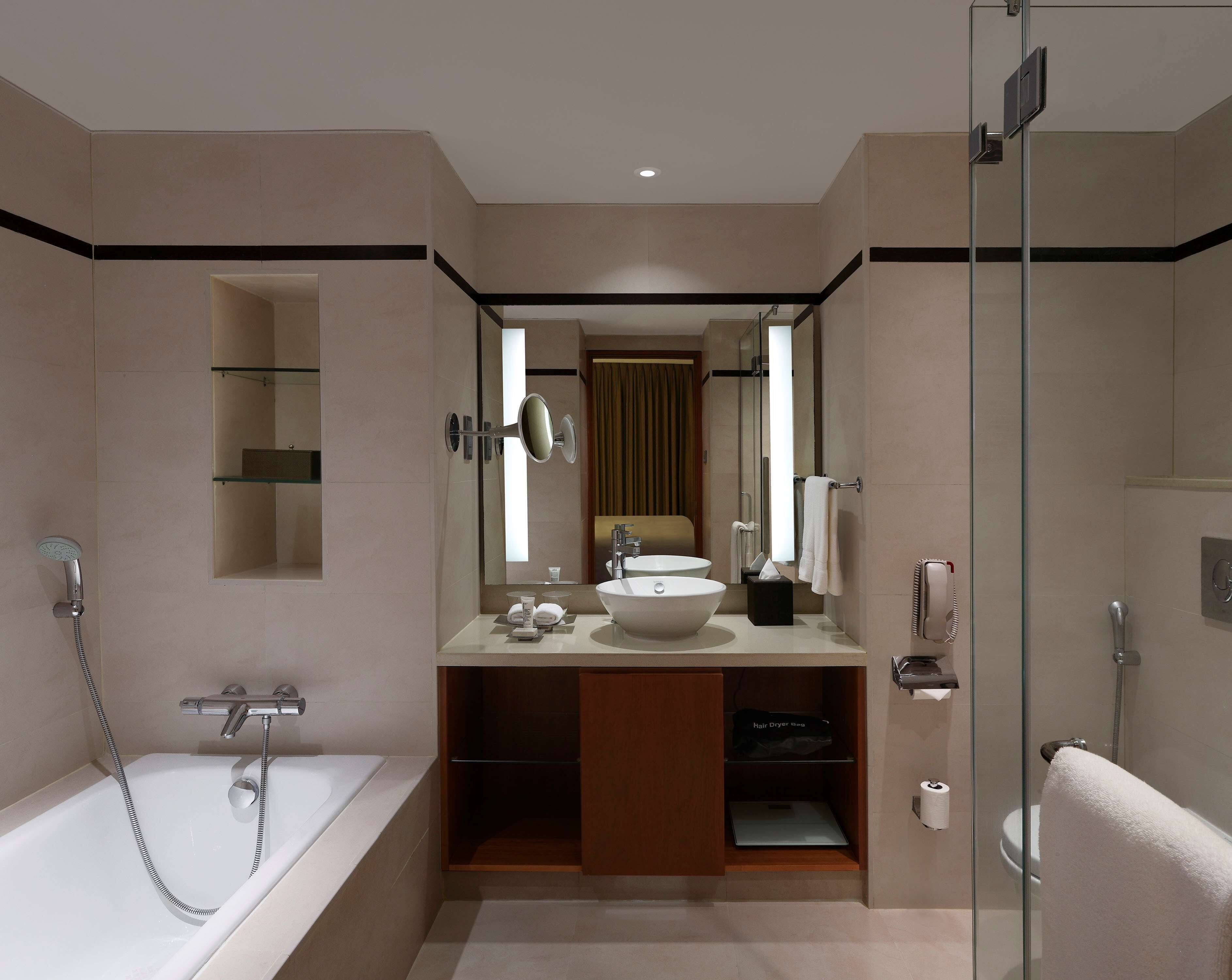 Une salle de bain moderne avec une baignoire, un grand miroir, un lavabo et une douche.