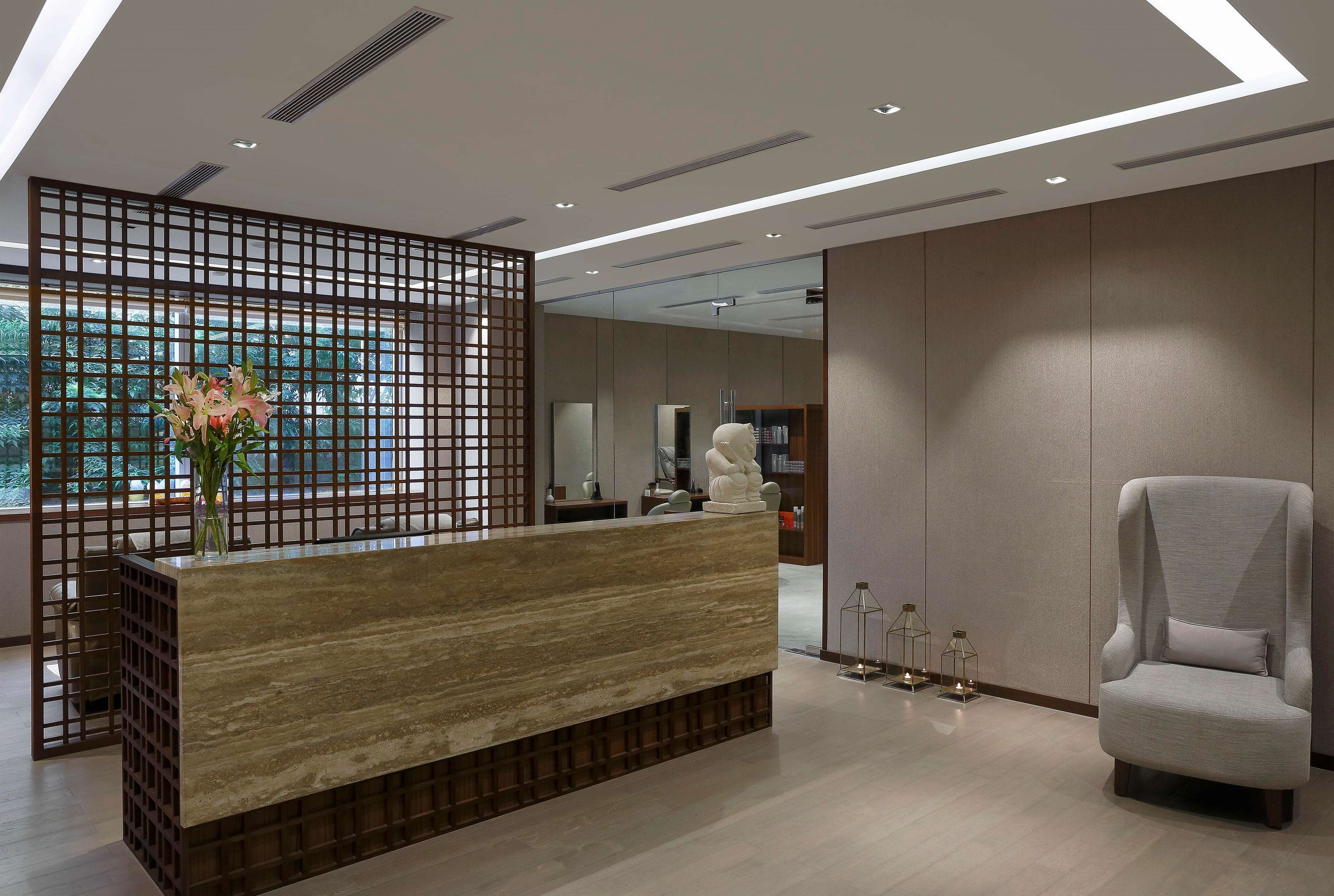 A reception area with a wooden reception desk, a white chair, and a decorative vase with flowers.