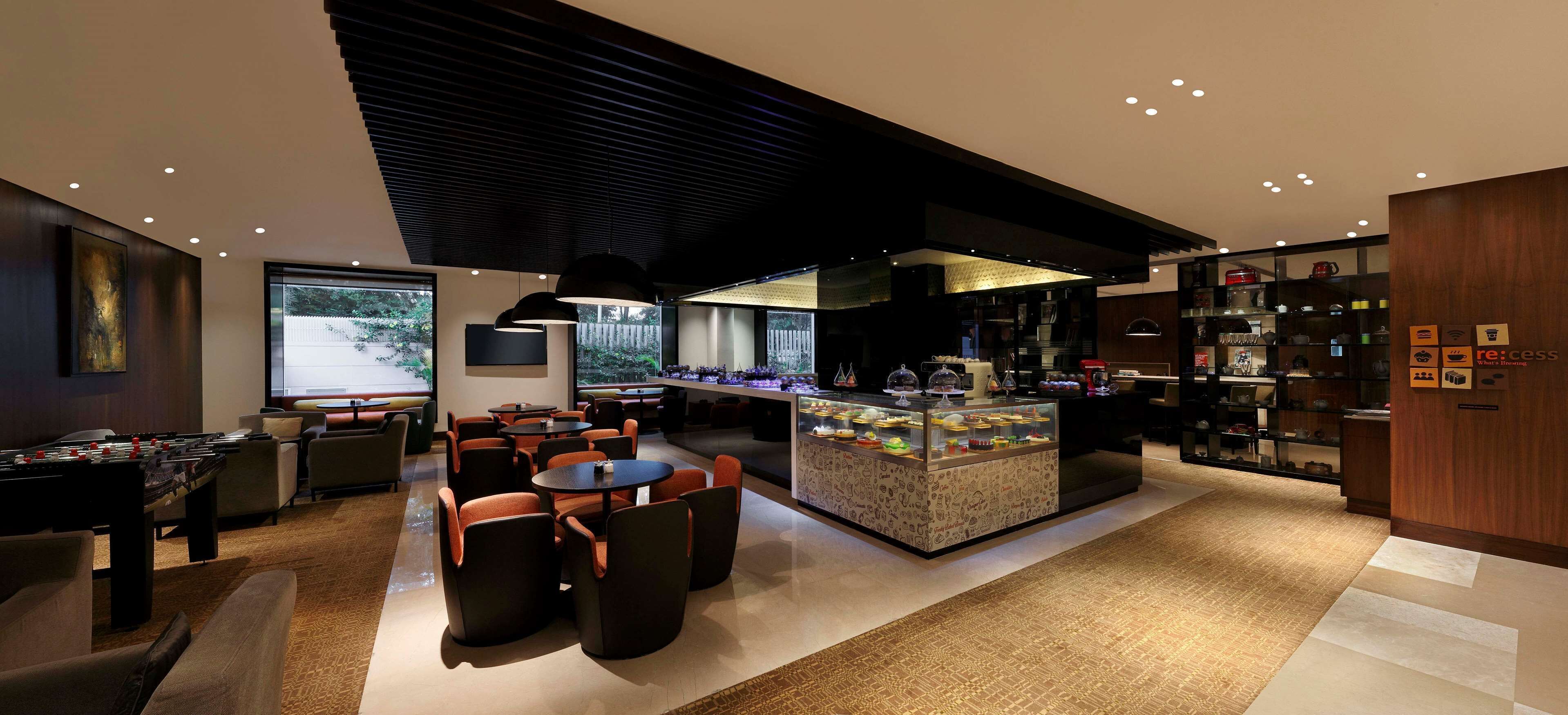 A modern restaurant with a bar area, seating, and a display case with food items.