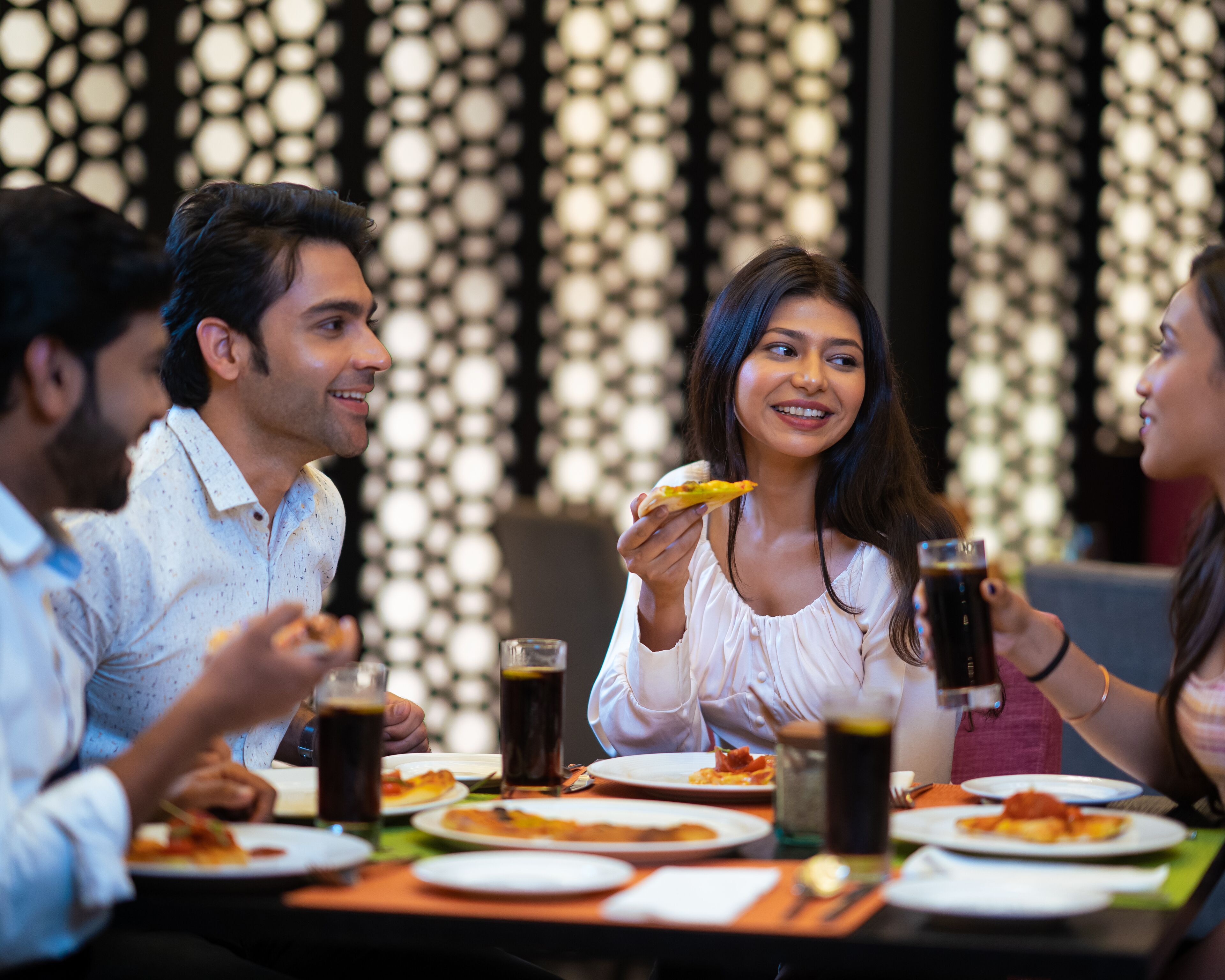 A group of people dining at a restaurant with a patterned wall in the background.