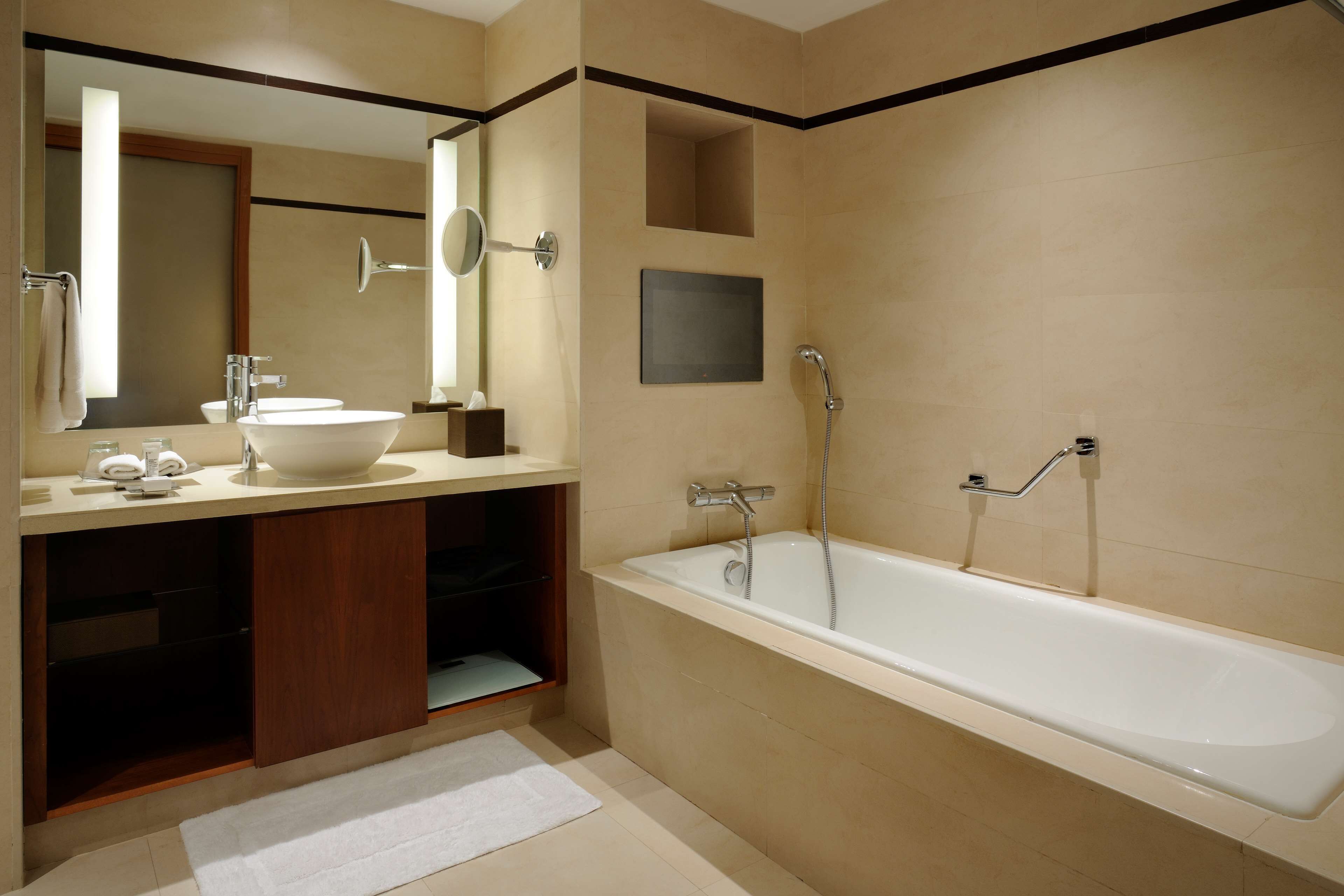 Un baño moderno con una bañera grande, un lavamanos y un espejo.