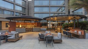 An outdoor patio area with seating arrangements, a bar, and a restaurant. - Hilton Bangalore Embassy GolfLinks (Bengaluru)