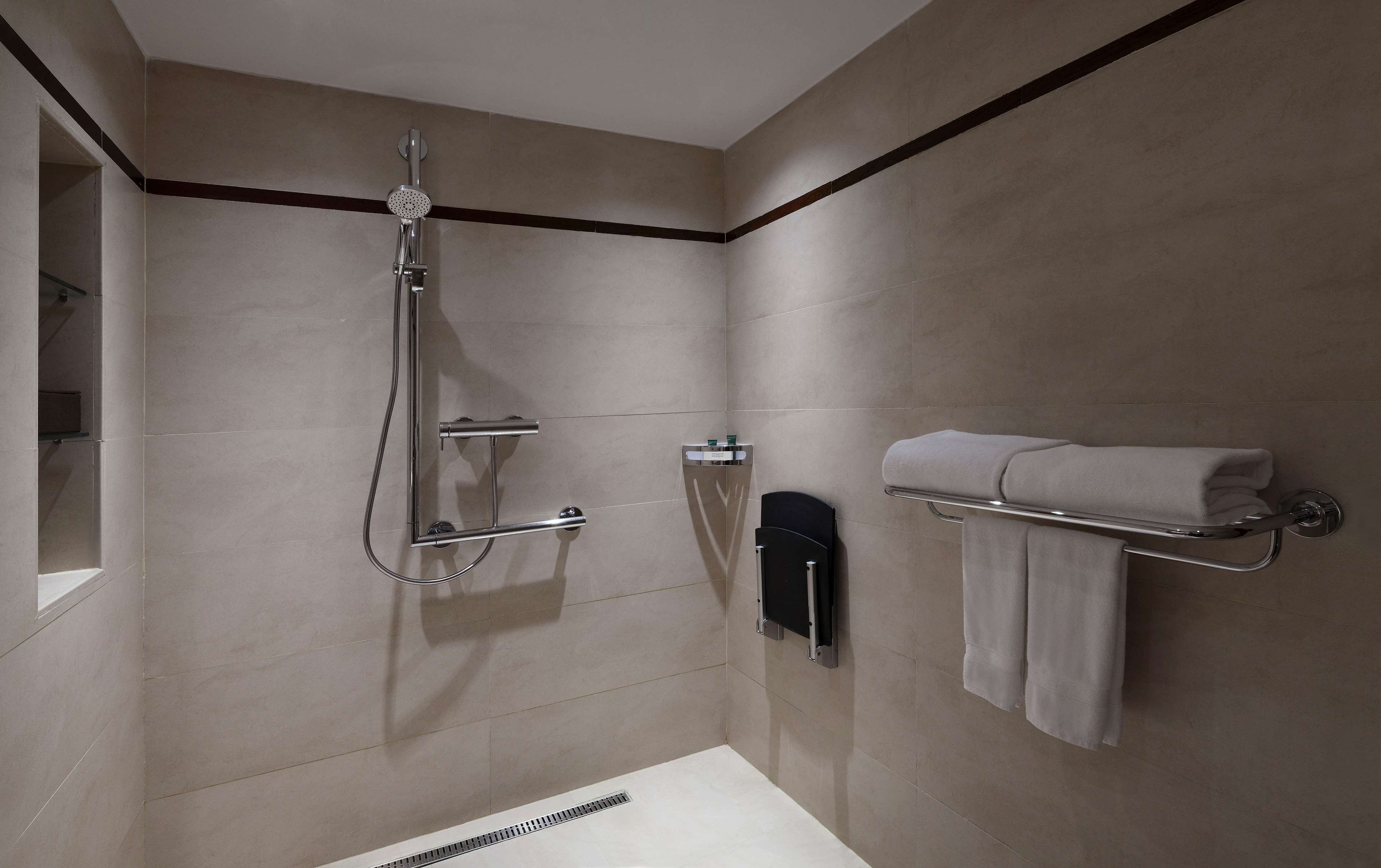 Une salle de bain moderne équipée d’une douche, d’un porte-serviettes et de toilettes.
