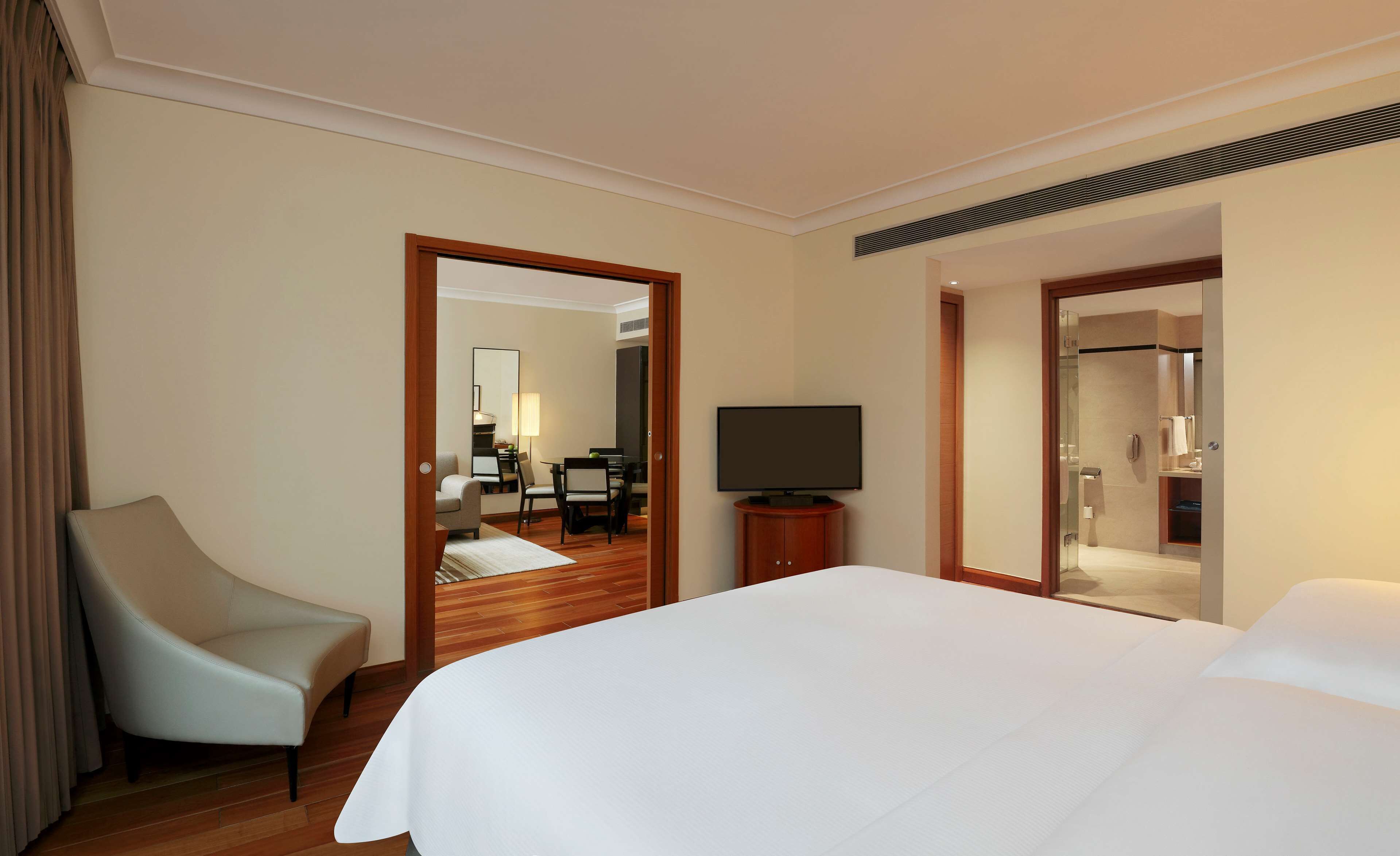Een hotelkamer met een bed, een televisie, een stoel en een badkamer, zichtbaar door een geopende deur.