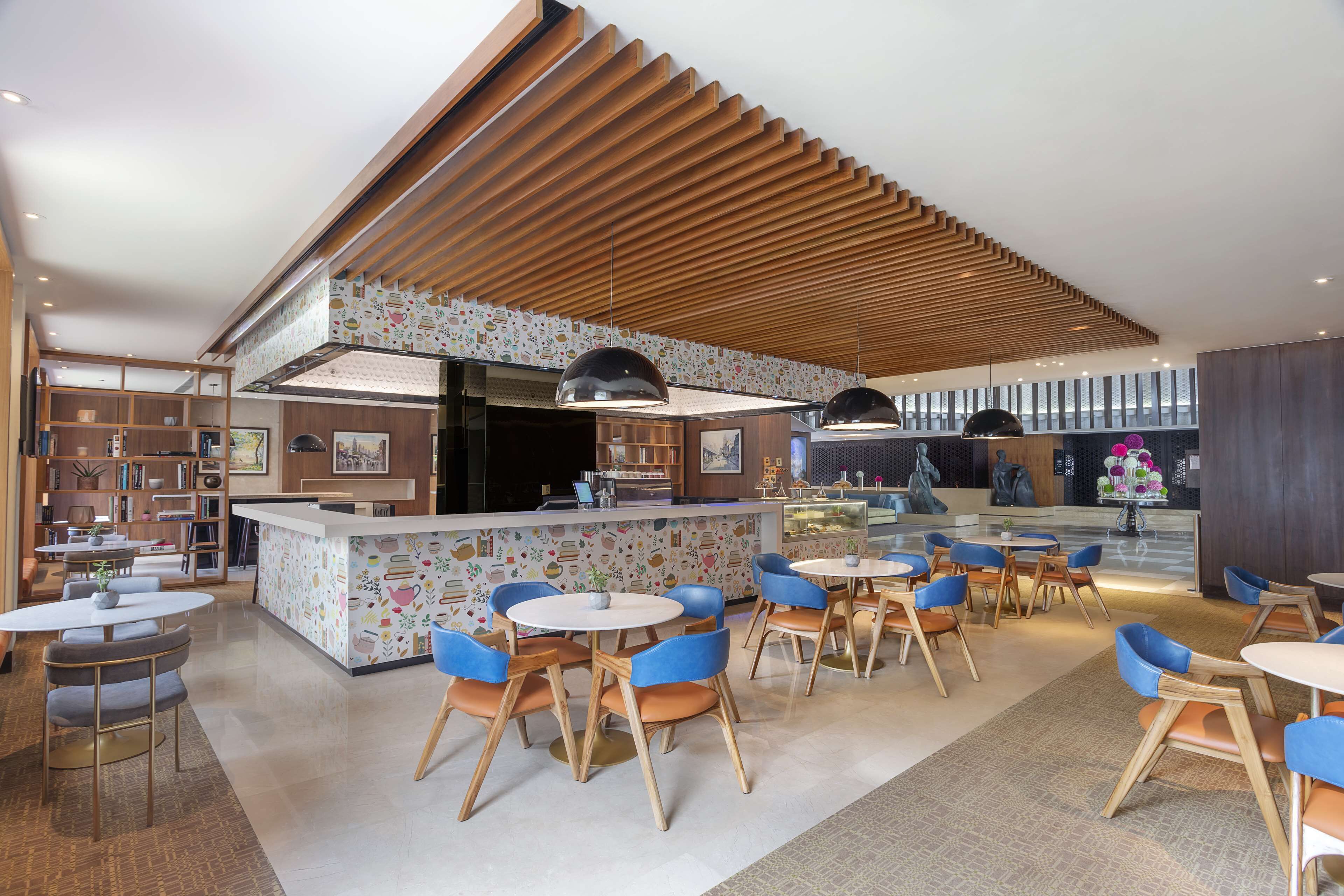 A modern restaurant with a central island, blue chairs, and a patterned ceiling.