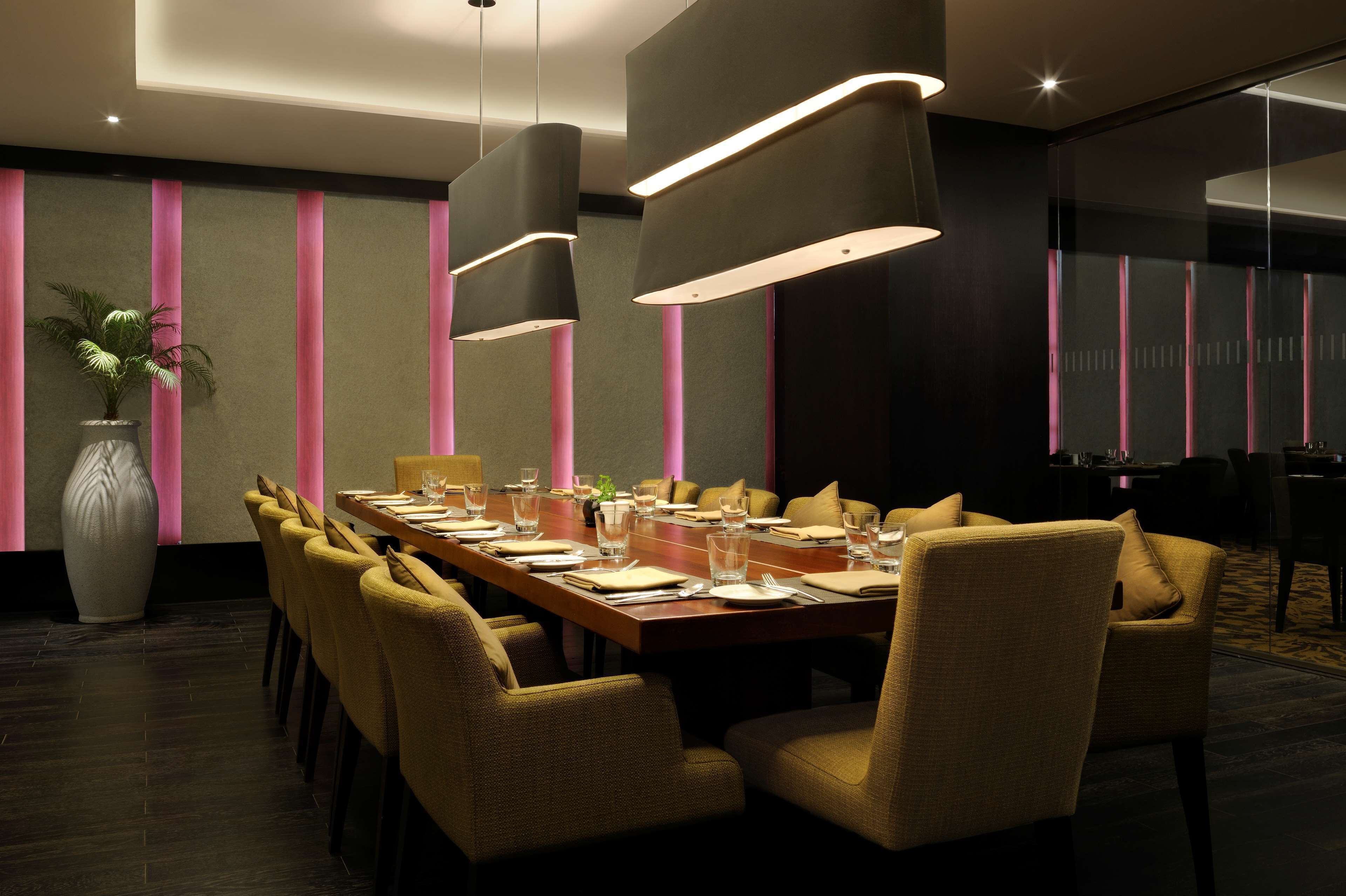 A conference room with a long table, chairs, and modern pendant lighting.