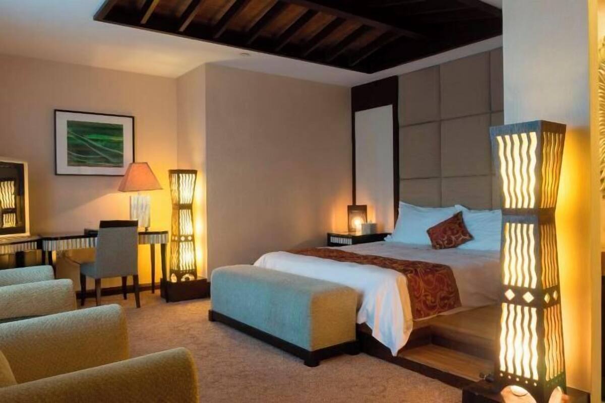 Una habitación de hotel con cama, mesitas de noche, escritorio y una silla.