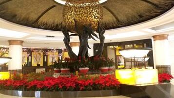 A lobby with a central fountain, potted plants, and a reception desk.