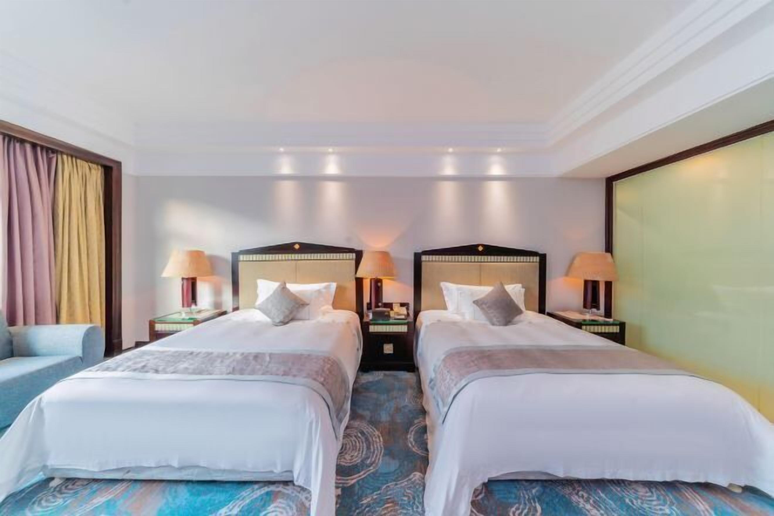 A hotel room with two beds, a sofa, and a large window.