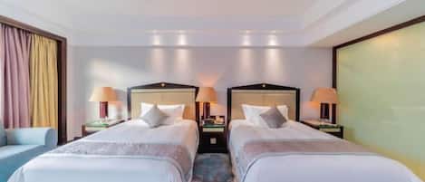 A hotel room with two beds, a sofa, and a large window.