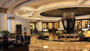 A spacious lobby with a central fountain, polished marble flooring, and a reception desk.