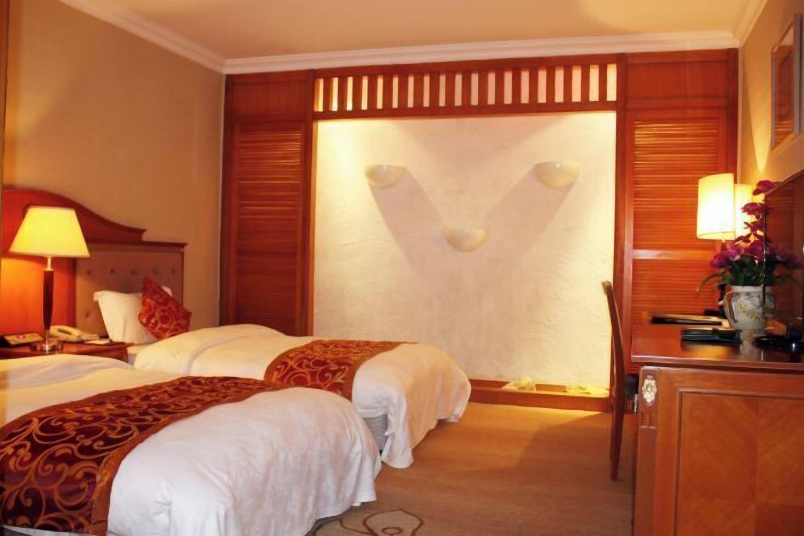 A hotel room with two beds, a desk, and a chair.