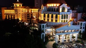 A large, illuminated hotel with a prominent dome and multiple wings, featuring a grand entrance and a parking area.