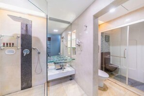 A modern bathroom with a glass shower enclosure, a glass sink, and a white toilet.