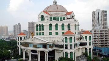 Un edificio grande e histórico con una cúpula destacada y numerosas ventanas, rodeado de modernos rascacielos.