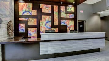 A reception desk with a modern design, featuring a marble-like countertop and a patterned wall behind it.