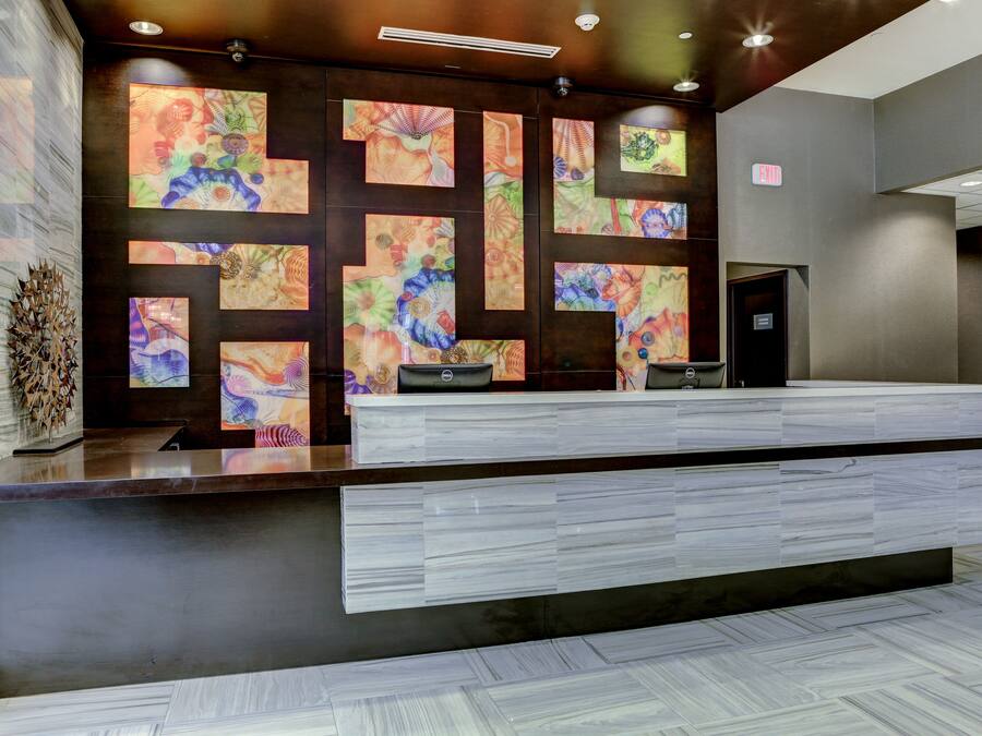A reception desk with a modern design, featuring a marble-like countertop and a patterned wall behind it.