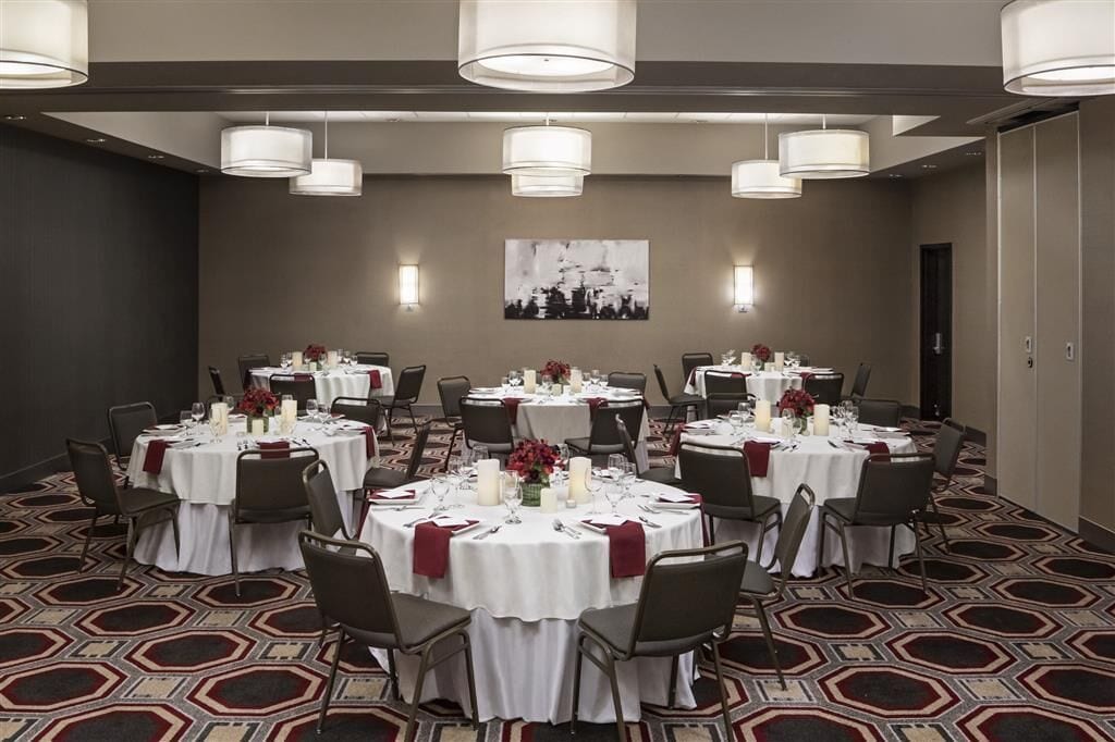 A conference room with round tables, white tablecloths, and grey chairs.