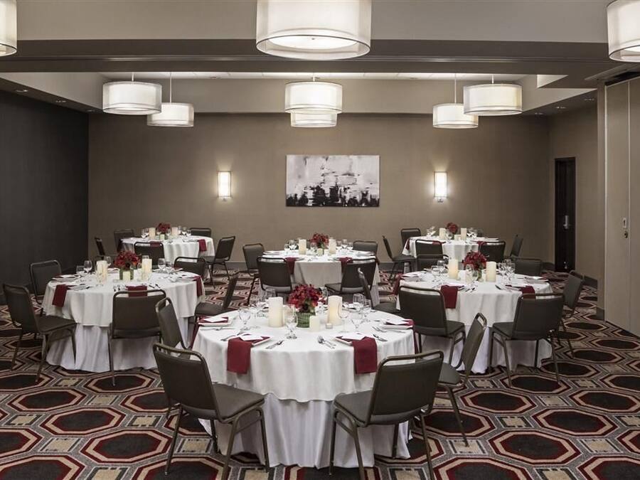 A conference room with round tables, white tablecloths, and grey chairs.
