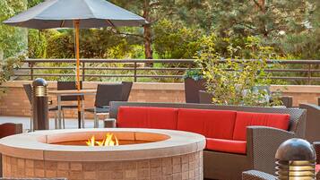 An outdoor patio area with a fire pit, seating, and a table.