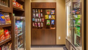 Un couloir dans un magasin, avec des distributeurs automatiques de collations et des vitrines réfrigérées.