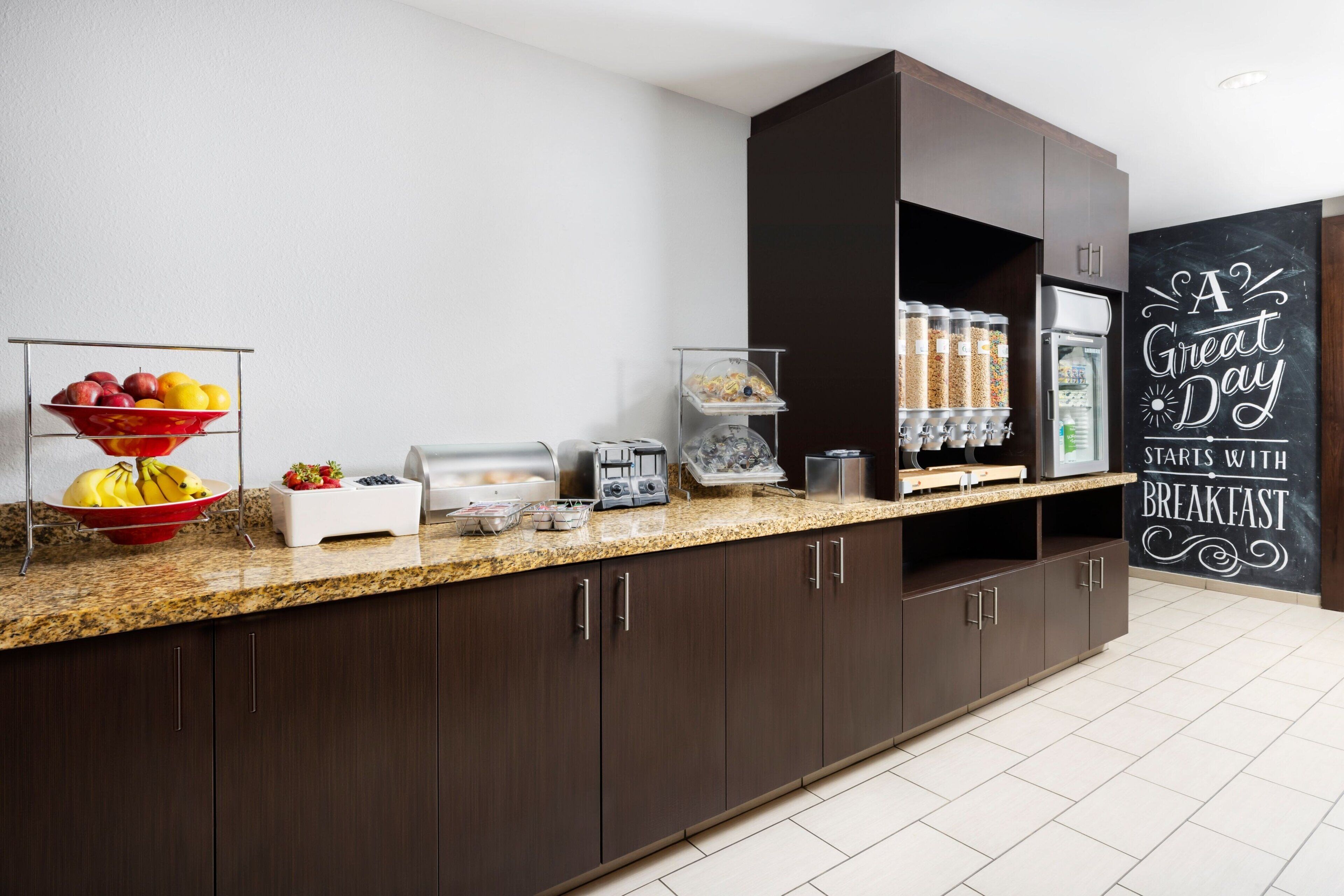 A modern kitchen with a granite countertop, a coffee machine, a toaster, and a refrigerator.