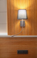 Una lámpara de pared con cuello flexible, un enchufe y un panel de control debajo.