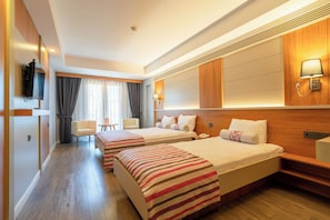 A hotel room with two beds, a desk, a chair, a TV, and a window with curtains.