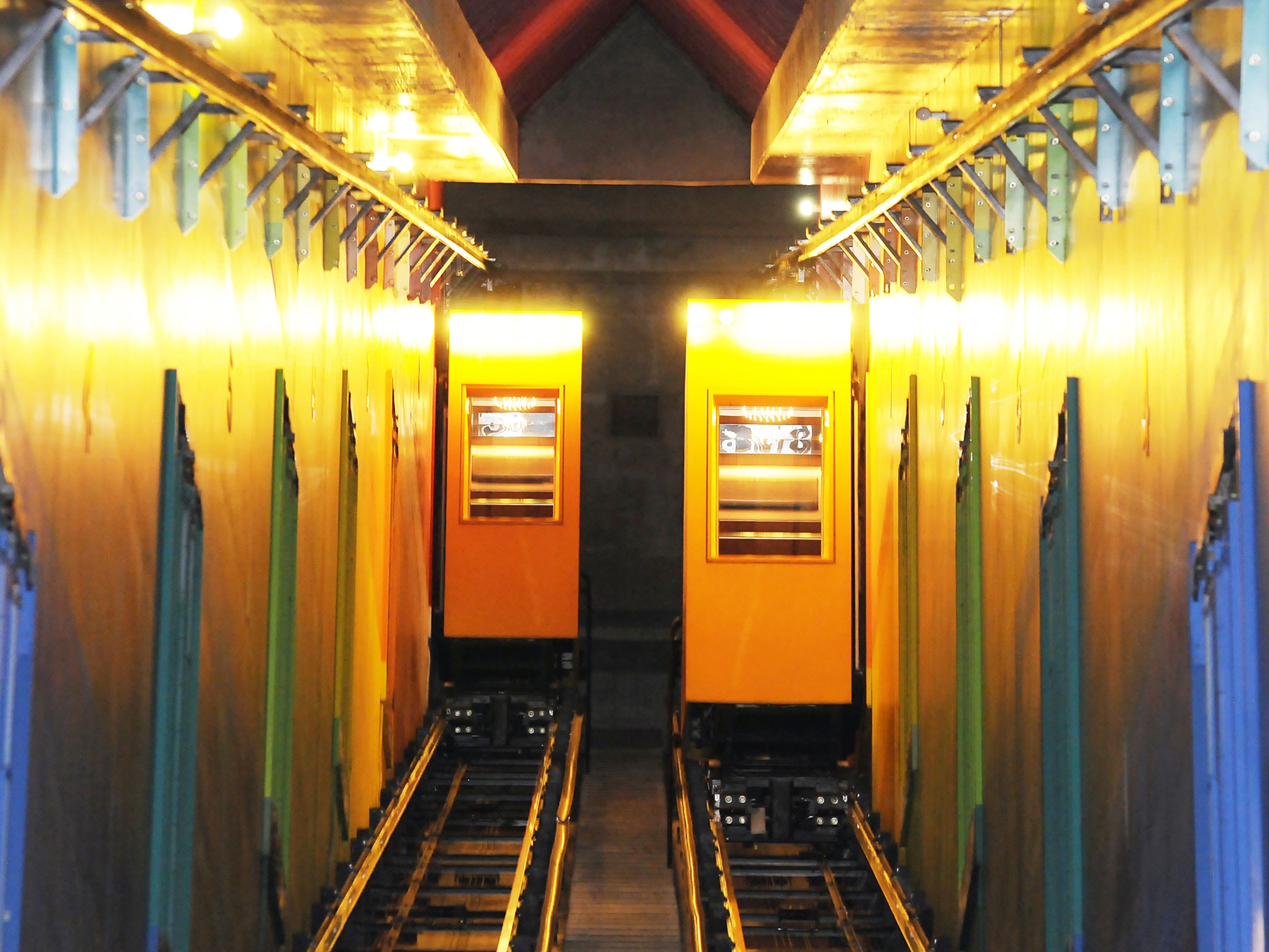 A train station platform with two yellow doors, overhead lighting, and metal railings.